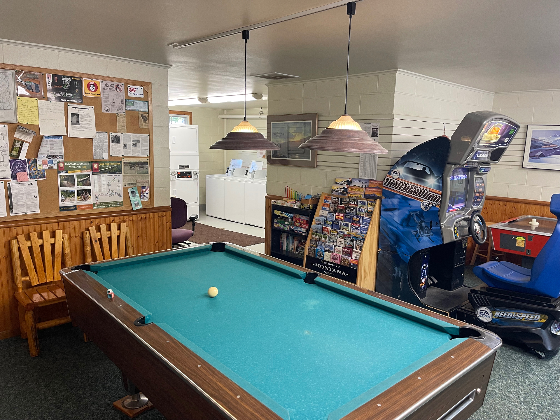Game room with pool table, Need for Speed Underground arcade cabinet and travel brochure display