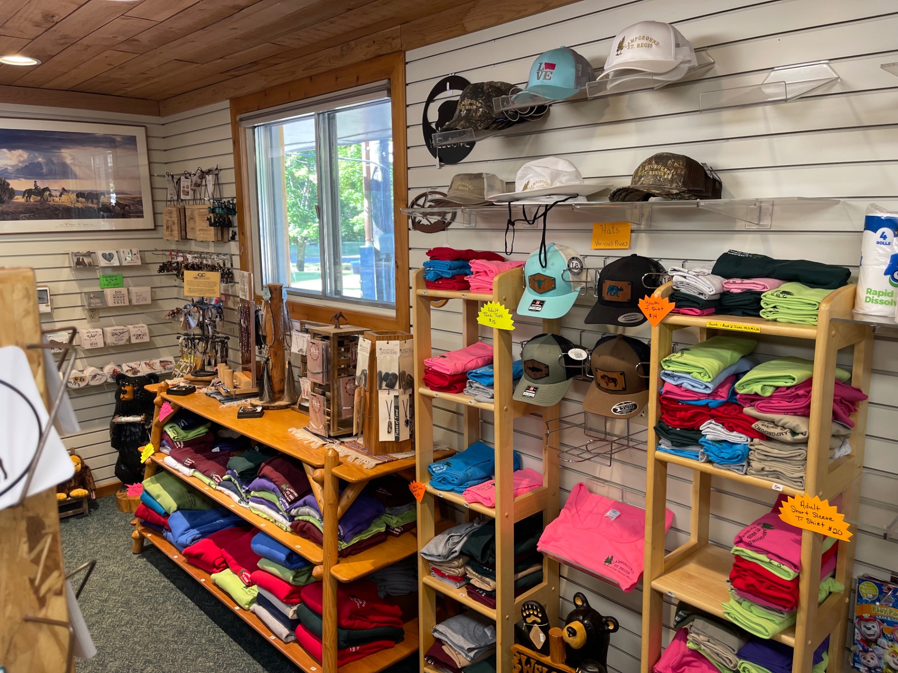 Campground St. Regis branded t-shirts, tank tops and trucker hats on wooden shelves