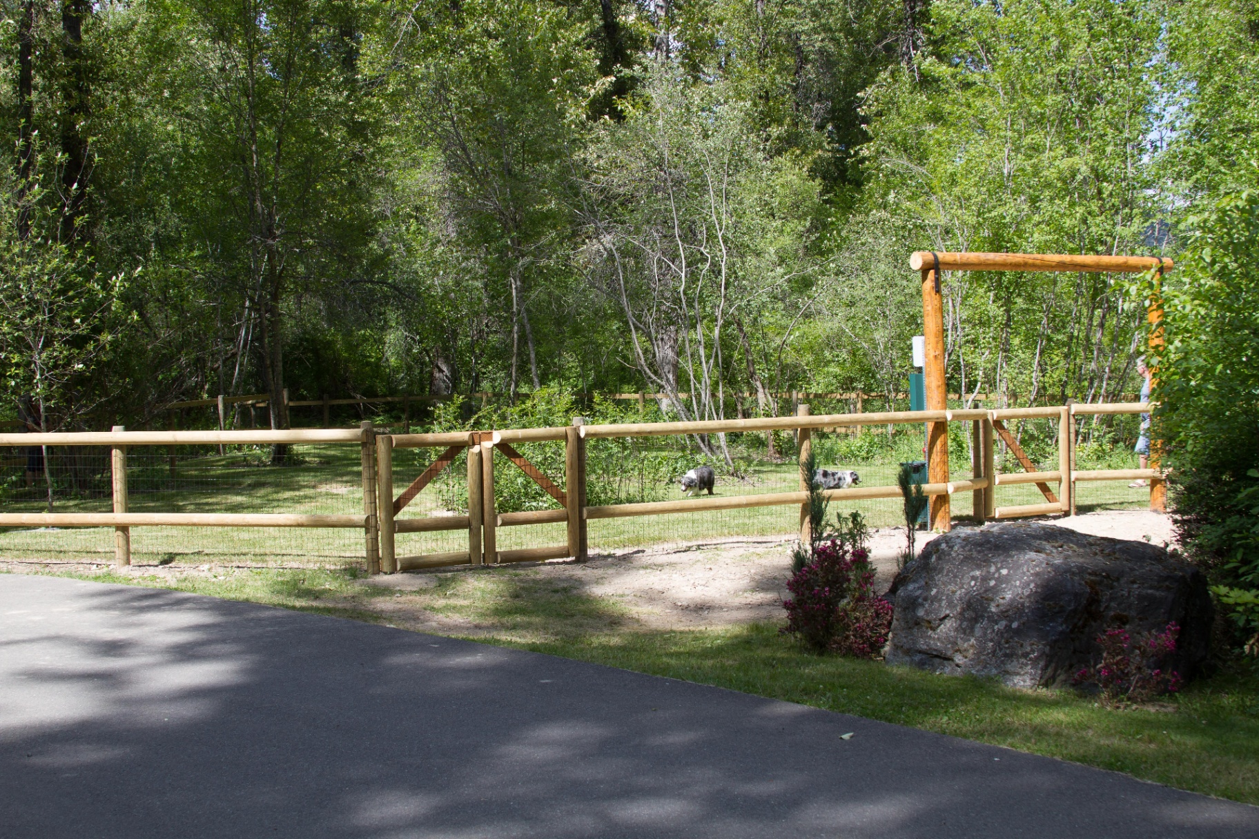 Wooden log gate and split-rail fence at the entrance to the off-leash dog park