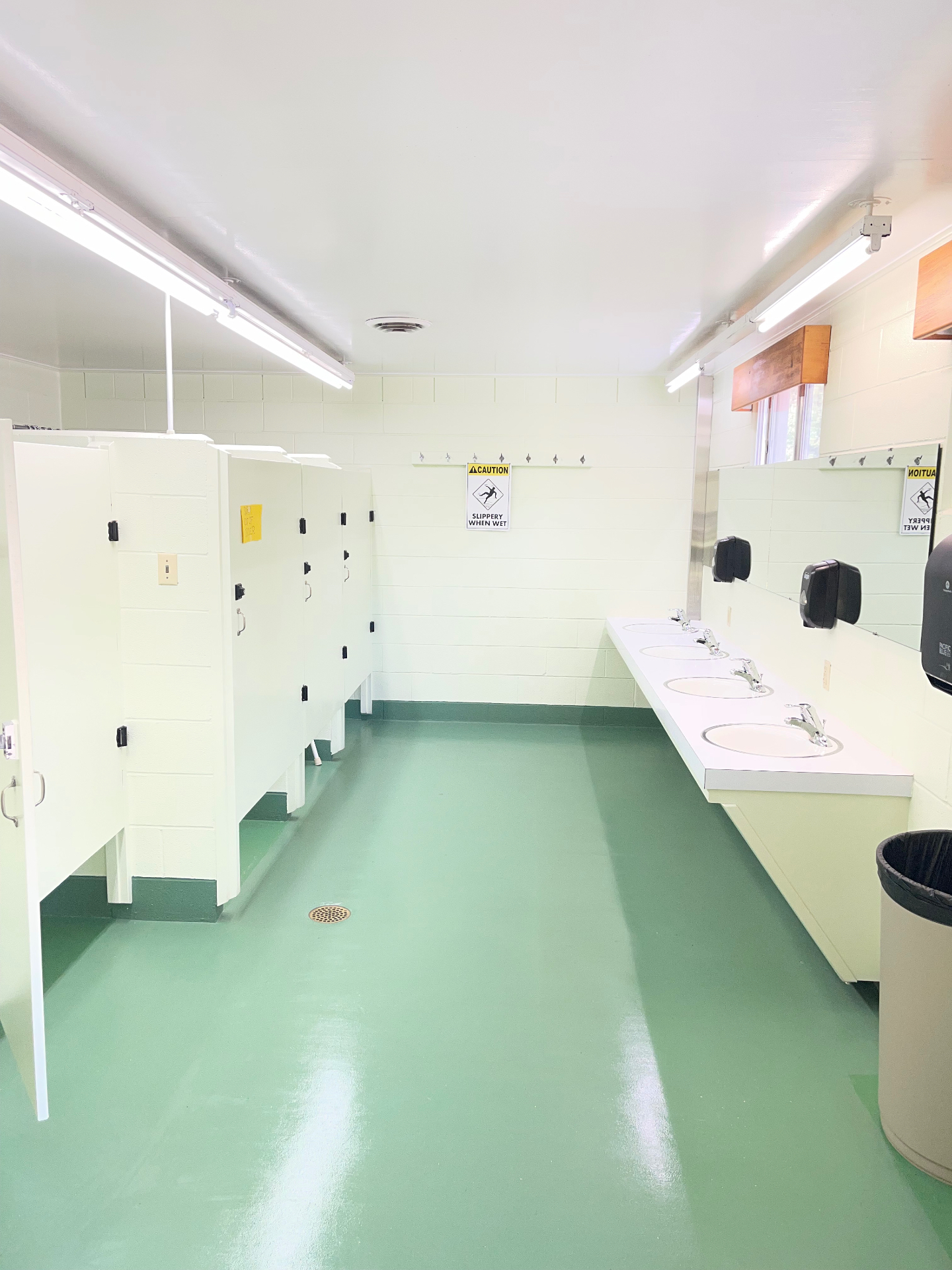 Clean bathhouse interior with private stalls, sink counter and green floors