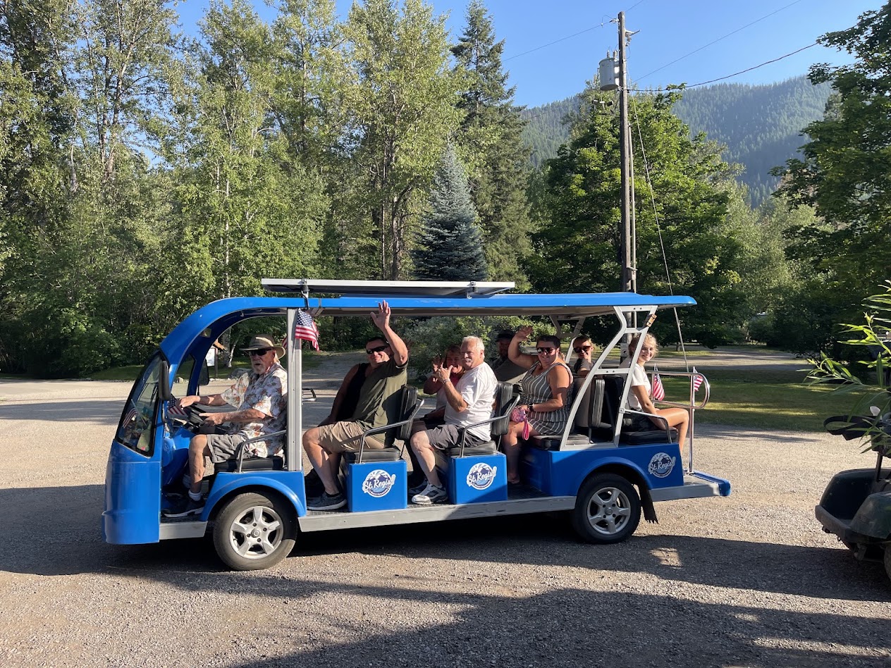 Guests waving from the blue Campground St. Regis town shuttle as it winds through the pines